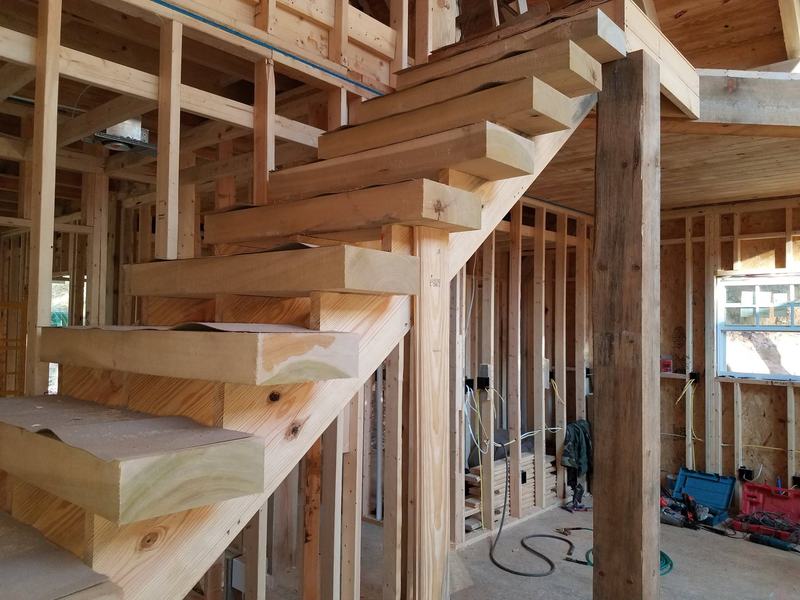 Thick wood stair treads on a heavy timber stringer inside a house under construction. Opens larger.