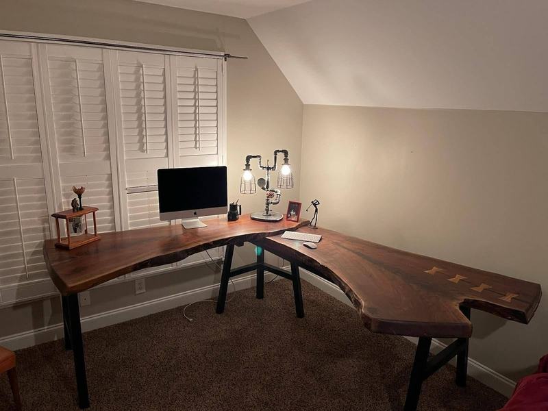 A dark live-edge slab desk with butterfly keys in a home office. Opens larger.